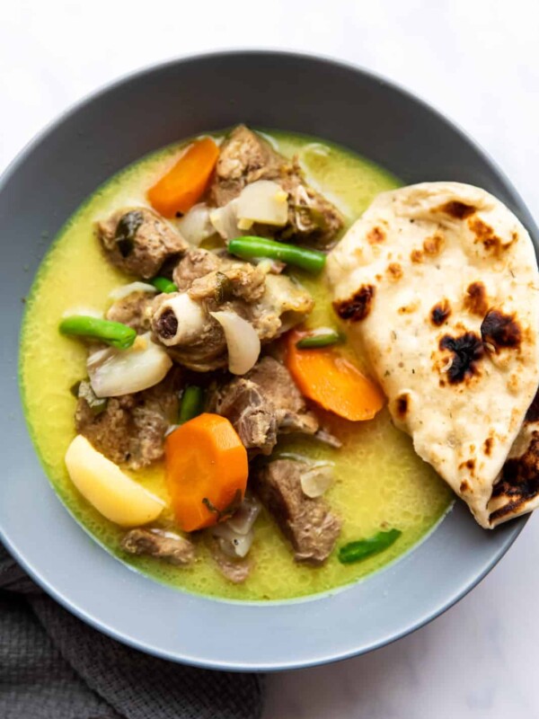 Mutton stew with coconut served in a bowl with naan bread