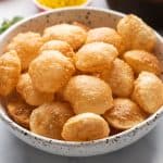 Puris served in a bowl with the pani and filling in the background
