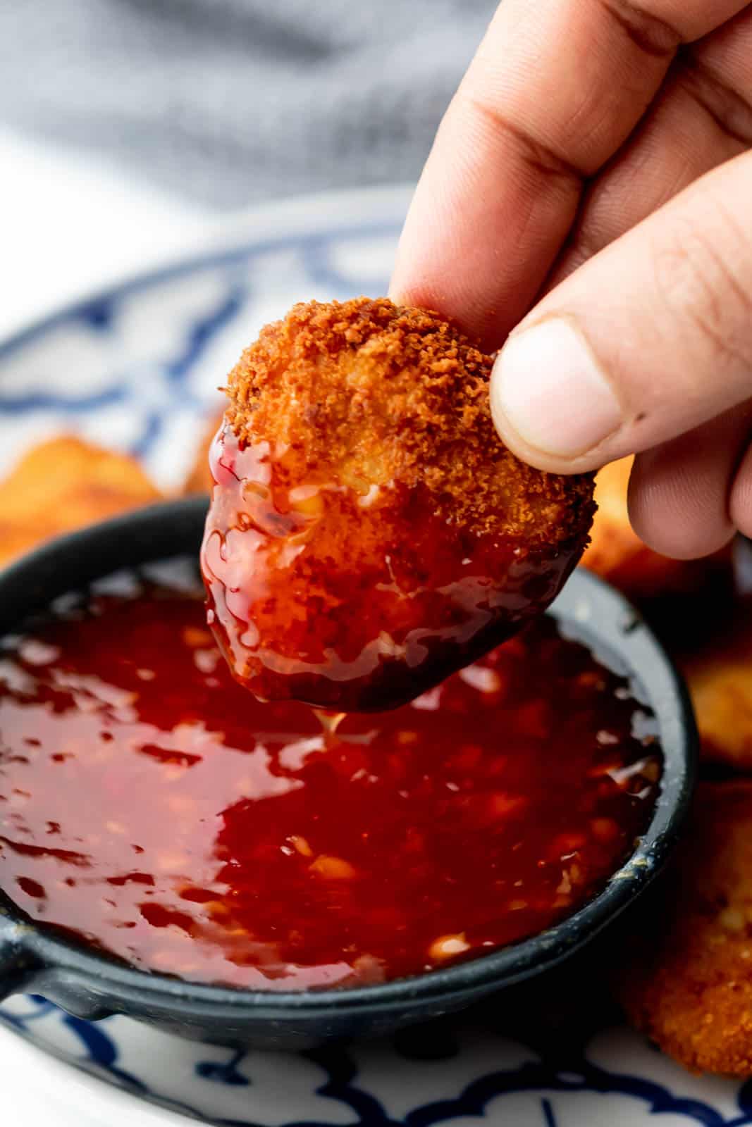 an image of a chicken nugget being dunked in thai sweet chilli sauce