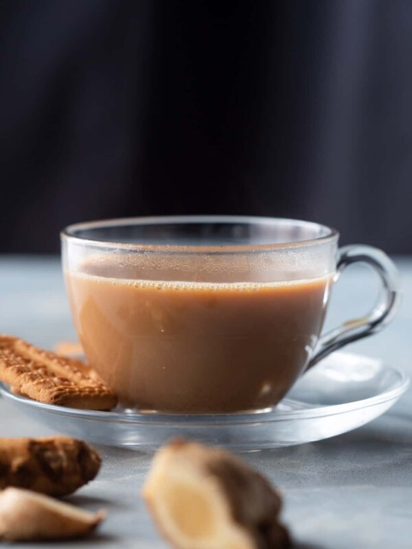 A cup of ginger chai with biscuits on the side