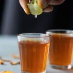 Lemon being squeezed into turmeric tea