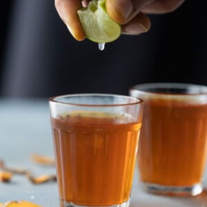 Lemon being squeezed into turmeric tea