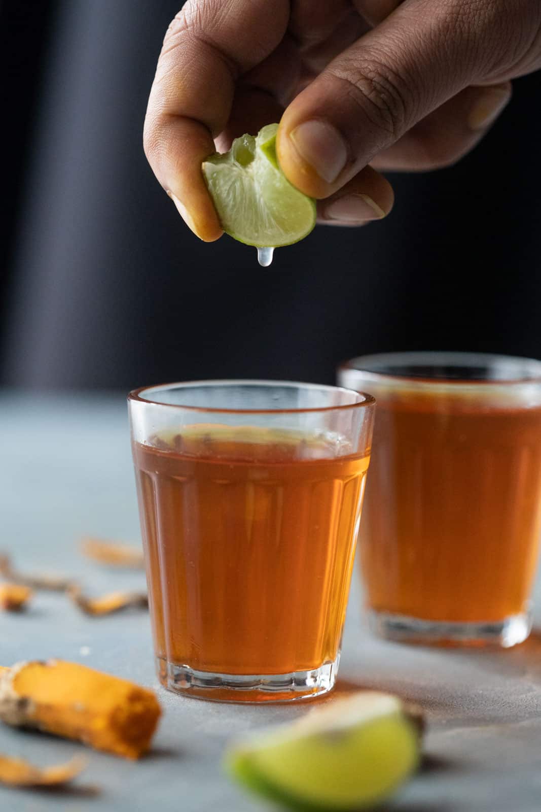 Lemon being squeezed into turmeric tea
