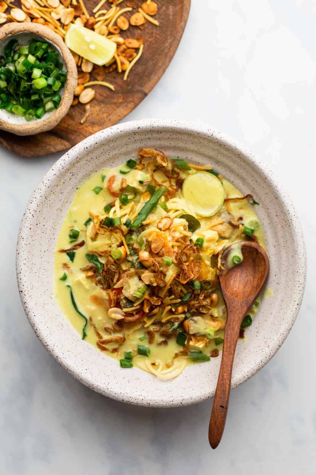 Burmese Khow Suey served in a white bowl with all the toppings and noodles