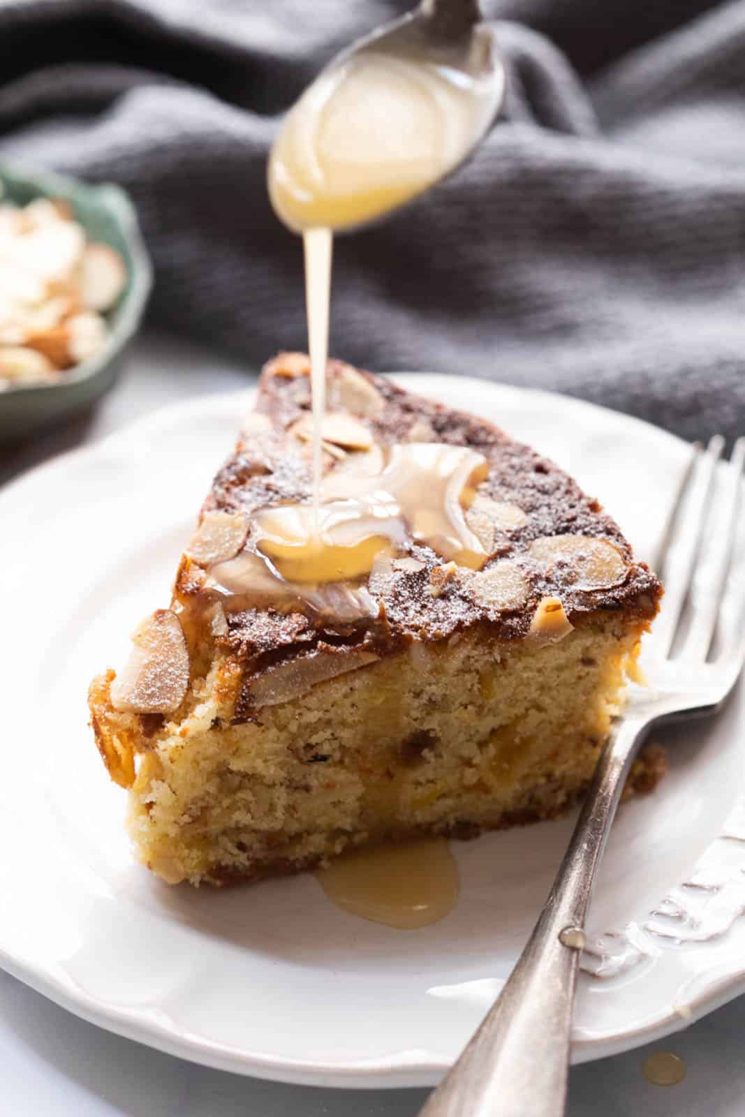 Pouring orange glaze over a slice of dundee cake on a plate