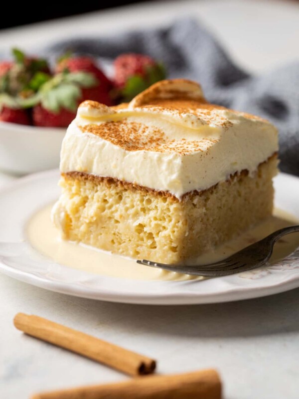 Eggnog tres leches served with strawberries on the side on a white plate