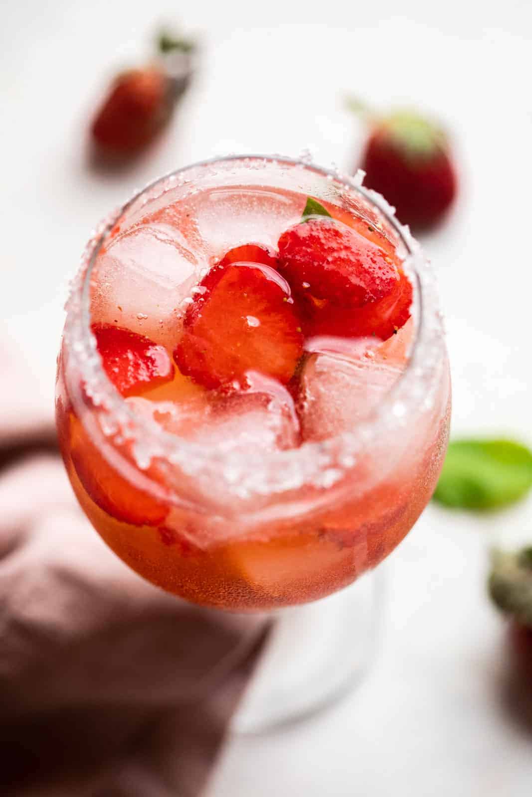 Strawberry Pepper Gin and Tonic served in a short stemmed glass with sugar on the rim