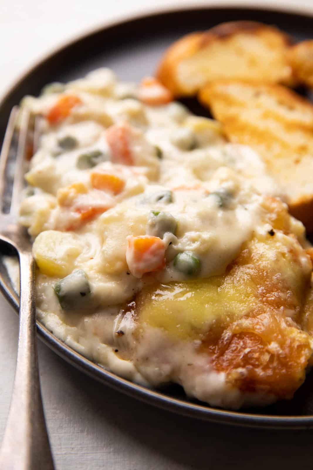 Veg Au Gratin served on a plate with slices of garlic bread