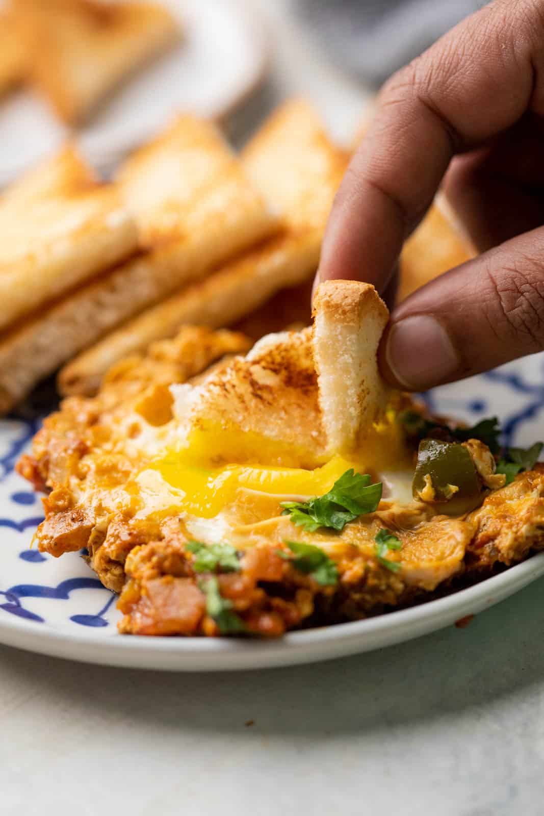 A slice of bread being dipped into the egg yolk