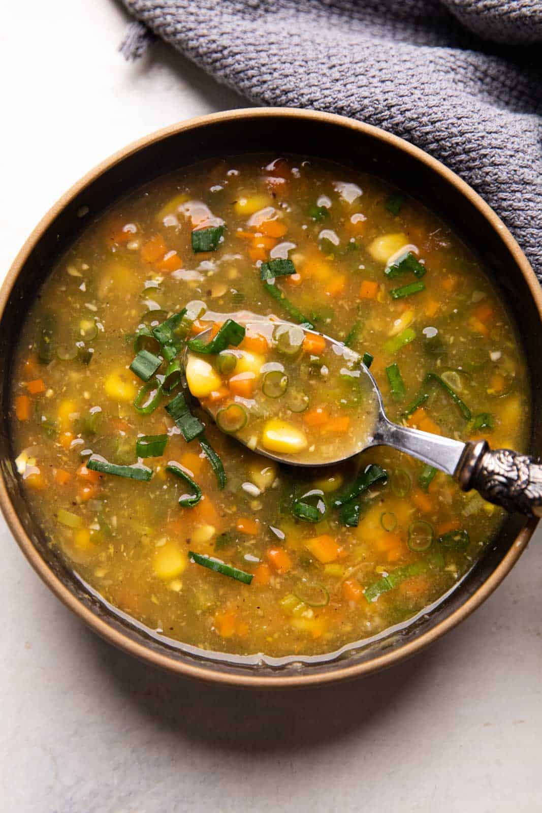Vegetarian Sweet Corn Soup served in a black bowl with a spoon