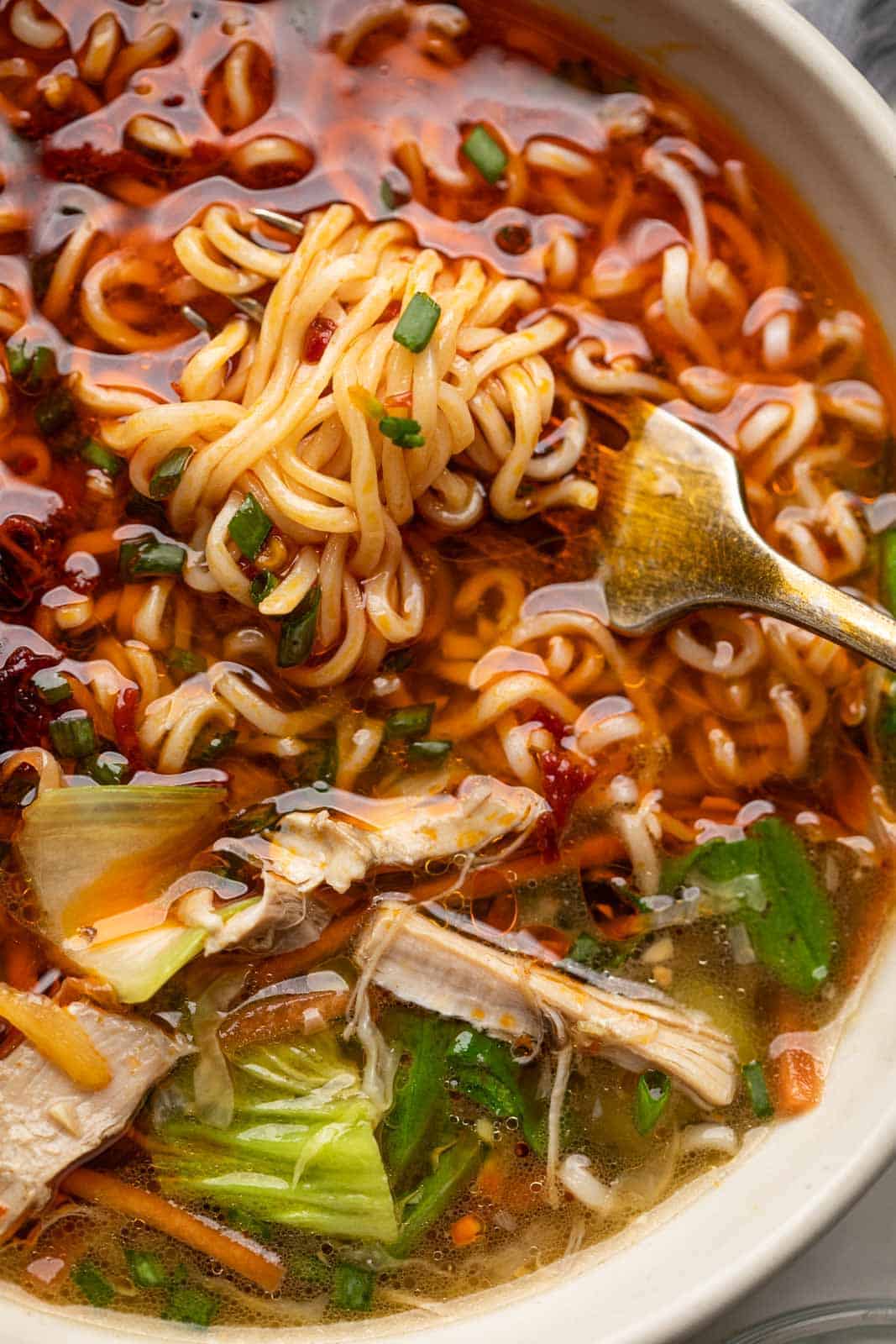 Closeup of noodles twirled around a fork in a bowl of chicken thukpa soup