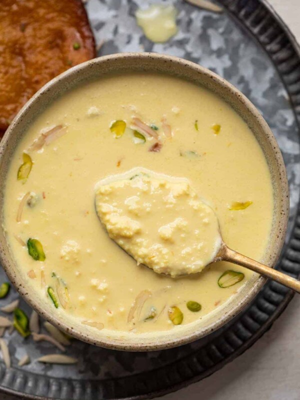 Close up of a spoon of instant rabdi in a brown bowl to show the creamy layers in the rabdi