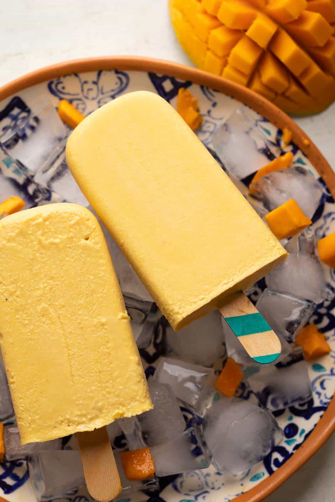 Mango kulfi served on a plate with diced mangoes