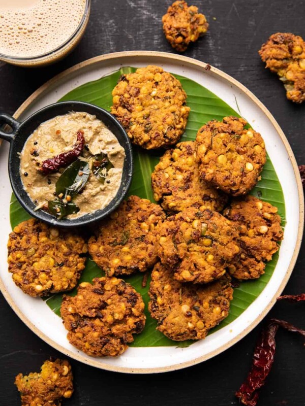 Crispy masala vadas served on a banana leaf lined white plate with coconut chutney on the side