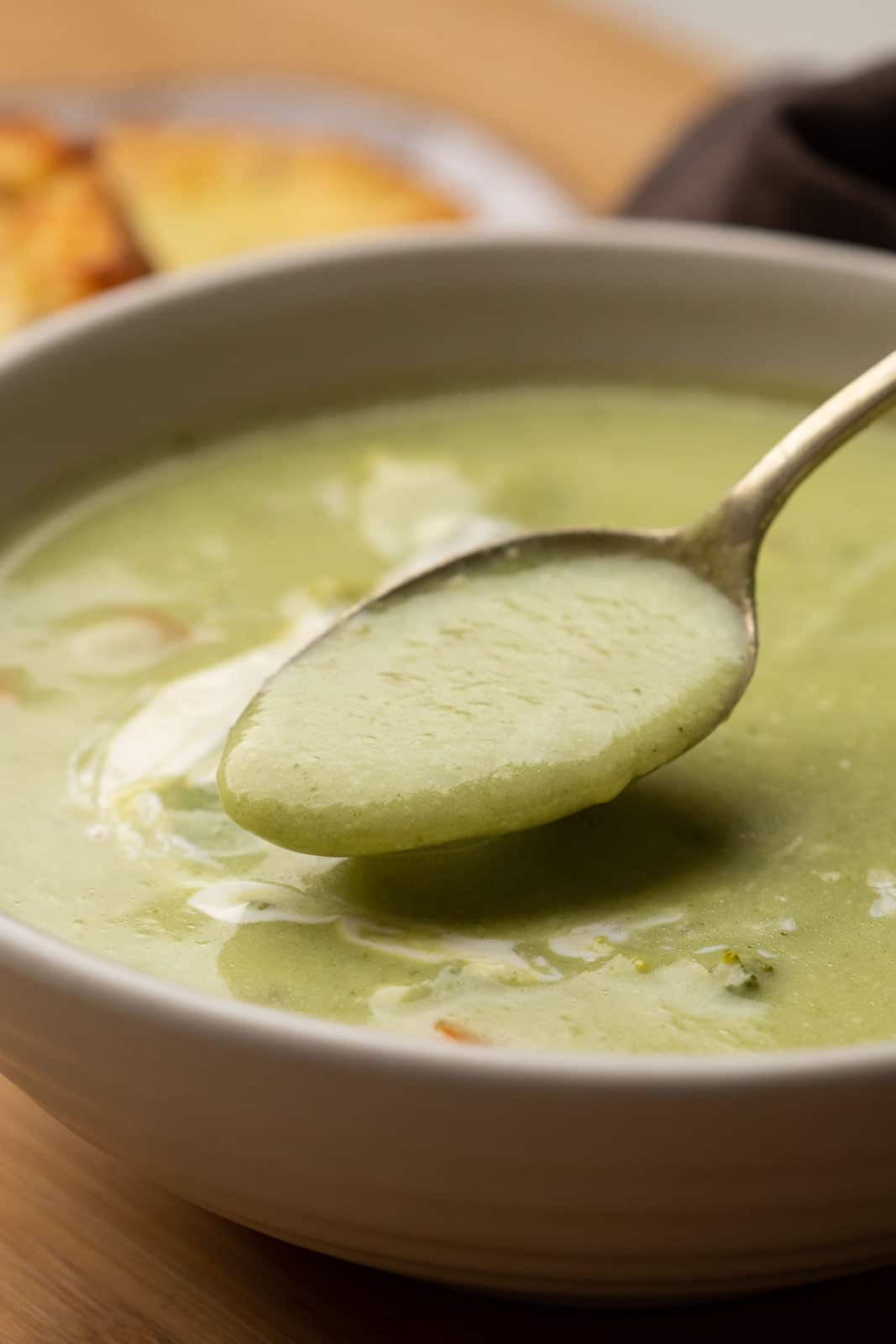 A spoon of healthy broccoli soup being taken out of the bowl