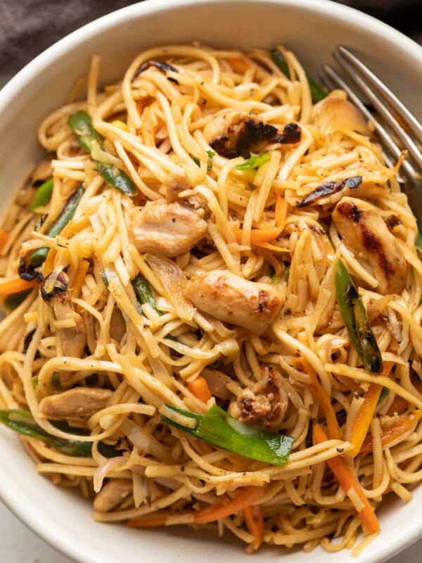 Chicken Chow mein served in a white bowl with a fork on the side