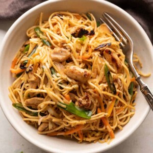 Chicken Chow mein served in a white bowl with a fork on the side