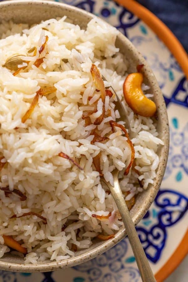 Closeup of ghee rice served in a brown bowl to show the texture of the rice