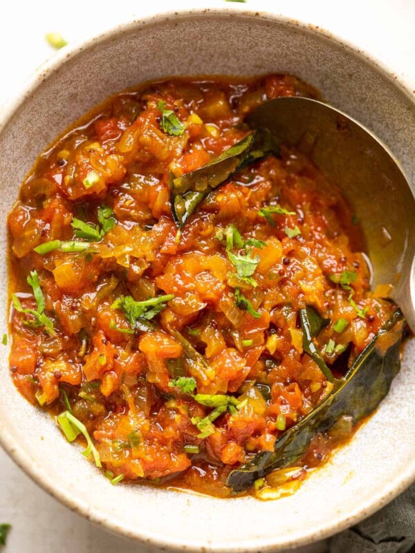 North Indian style tomato chutney served in a ceramic bowl with a spoon on the side