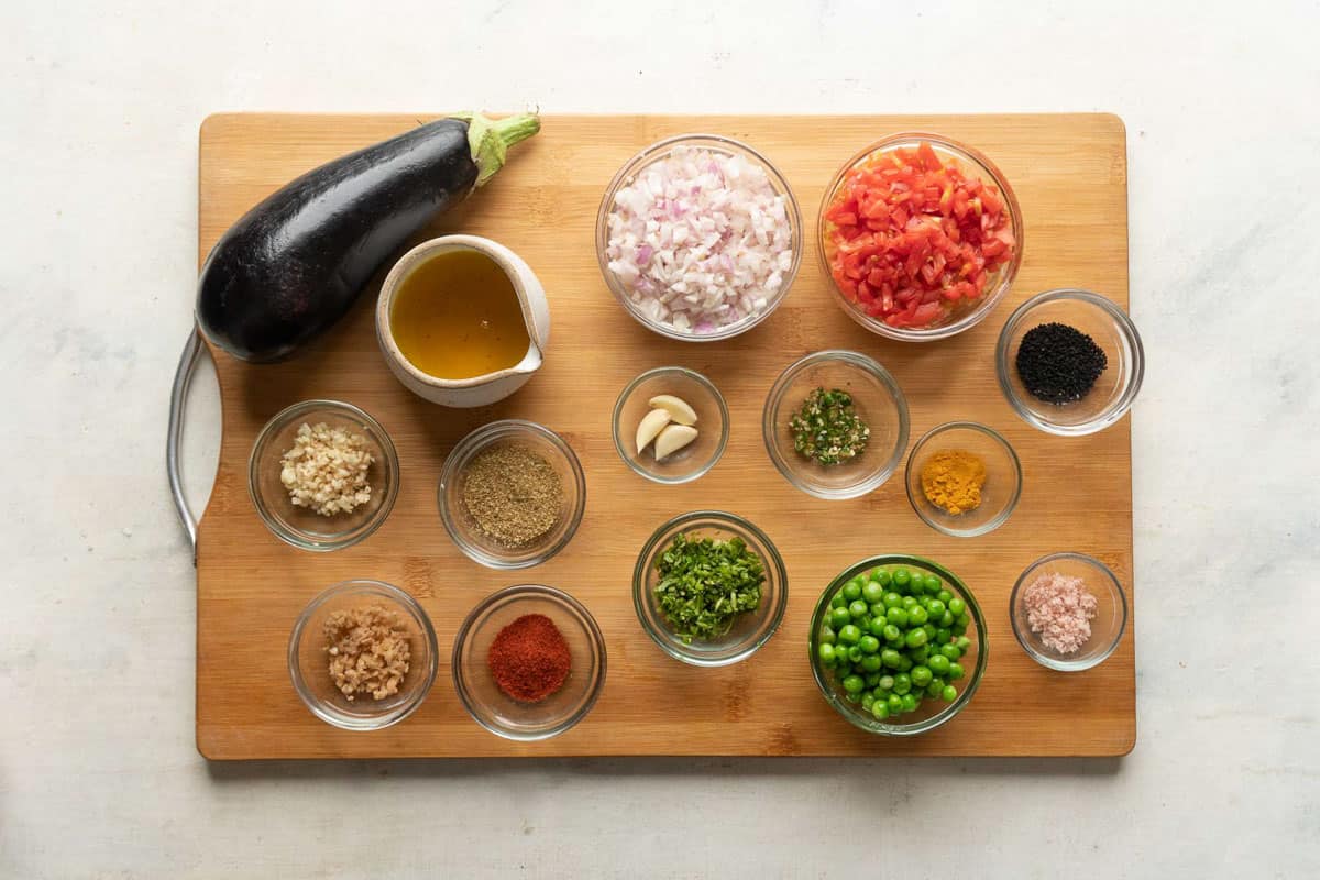 Ingredients for Baingan Bharta laid out on a wooden board