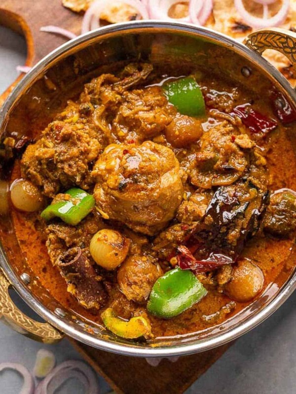 Kadai Chicken served in a copper kadai with tandoori roti and onions on the side