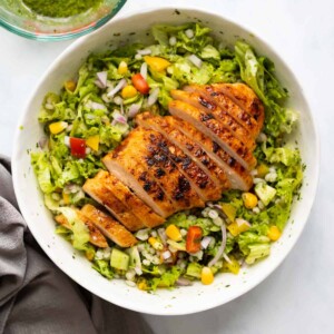 Barley chicken salad served in a white bowl with vinaigrette on the side