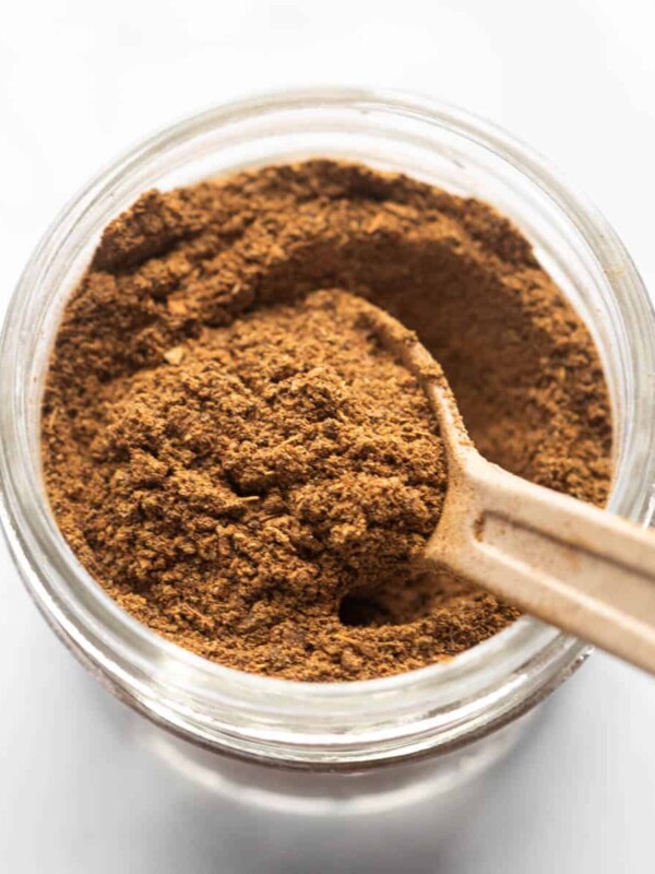 Garam Masala stored in a glass jar with a spoon in it
