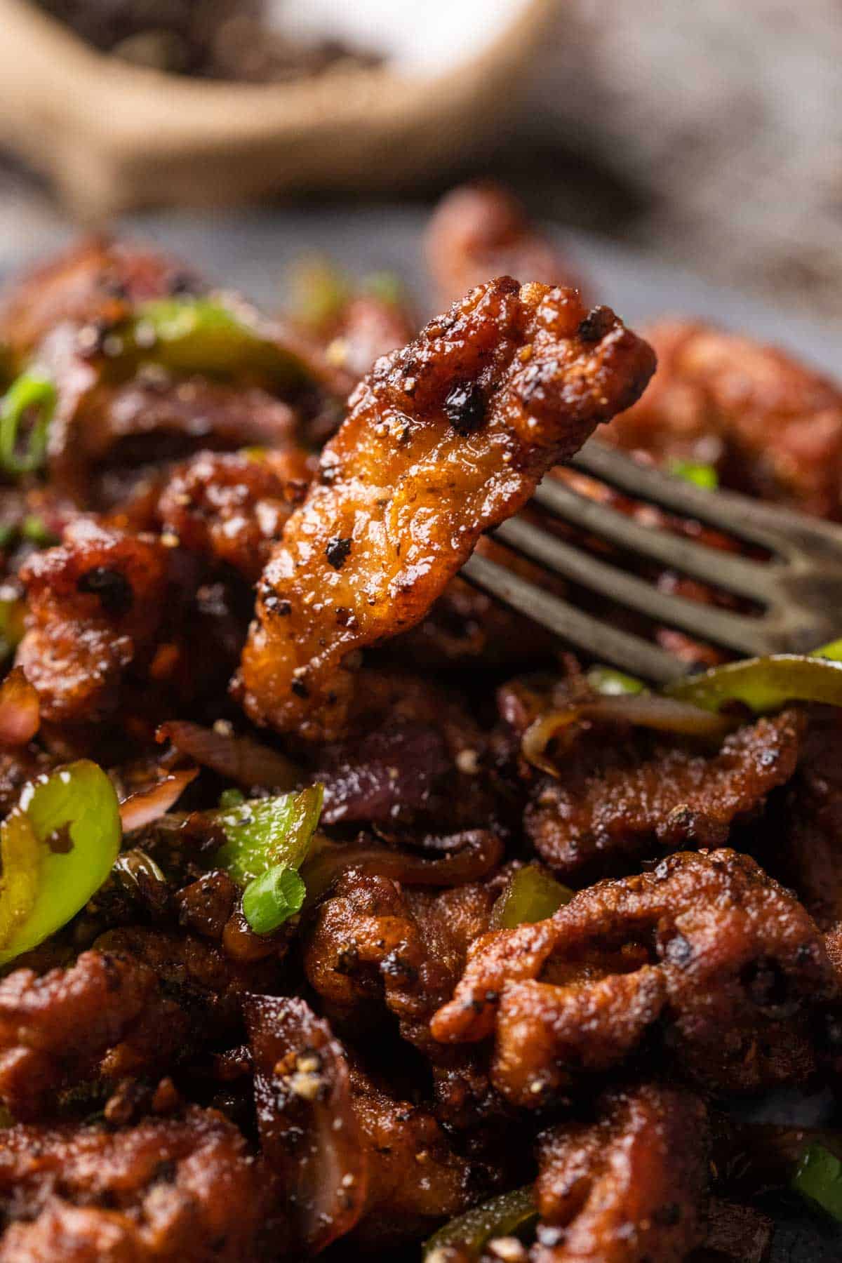 Closeup of a piece of salt and pepper chicken on a fork
