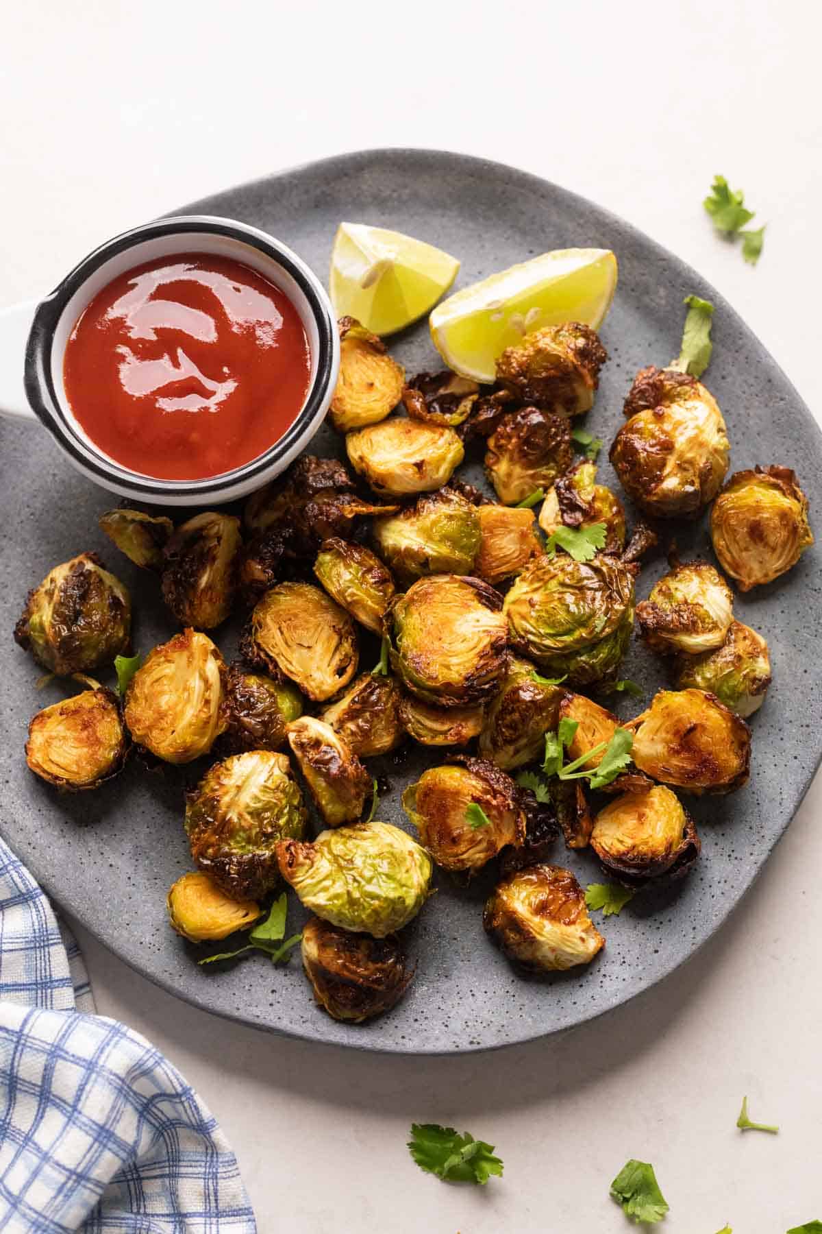 Roasted air fryer brussel sprouts served on a grey plate with ketchup on the side