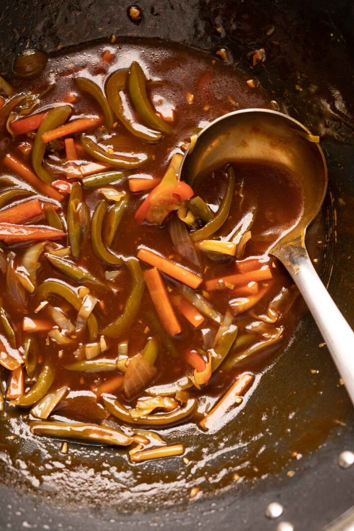 Sweet, sour tangy american chopsuey pictured in a wok with a ladle