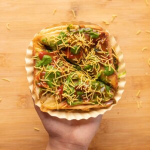 Picture of a hand holding bombay sandwich toast on a paper plate
