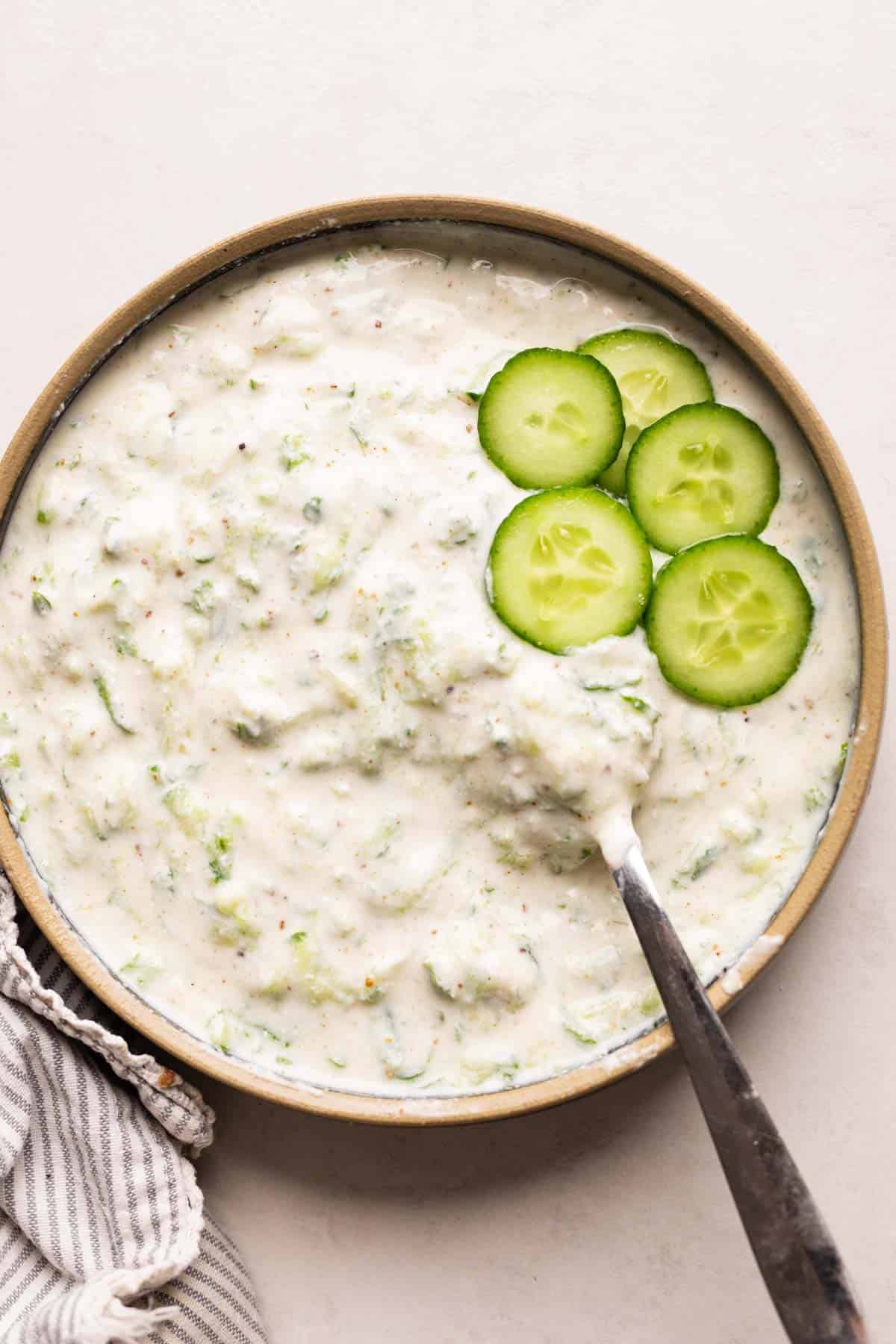 Cucumber Raita served in a bowl with sliced cucumber as garnish