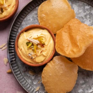 Mango Shrikhand served on a plate with pooris