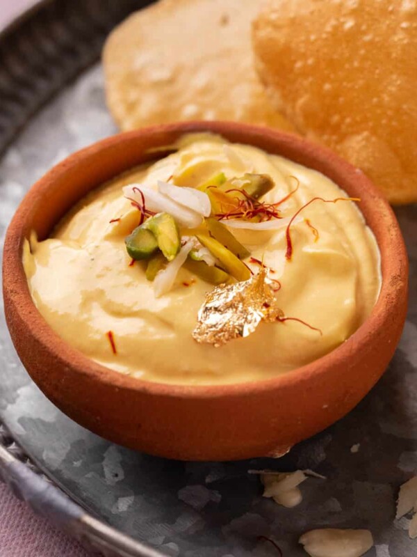 Mango Shrikhand served on a plate with pooris