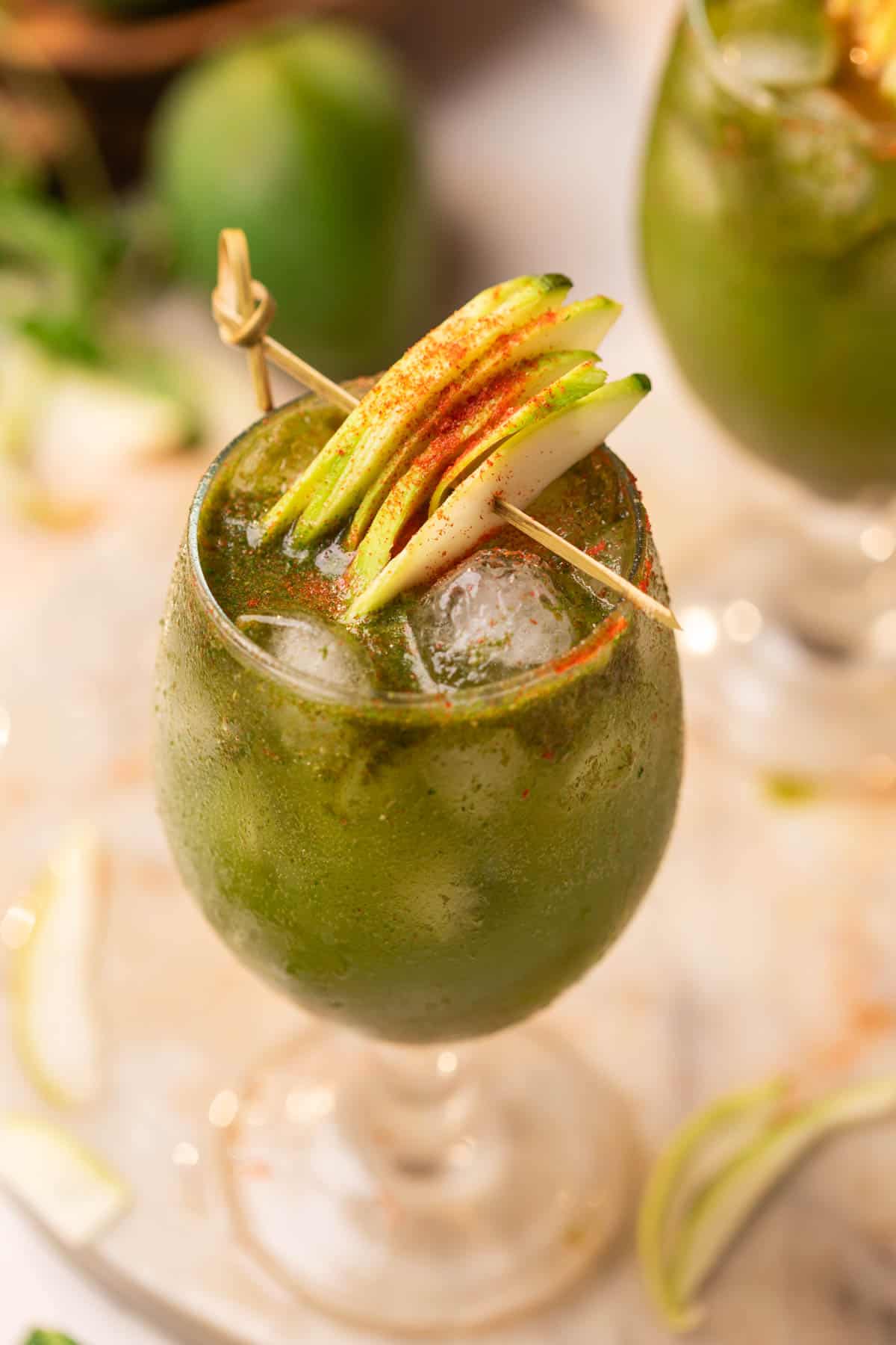 aam panna served in a glass and garnished with raw mango slices and chilli powder
