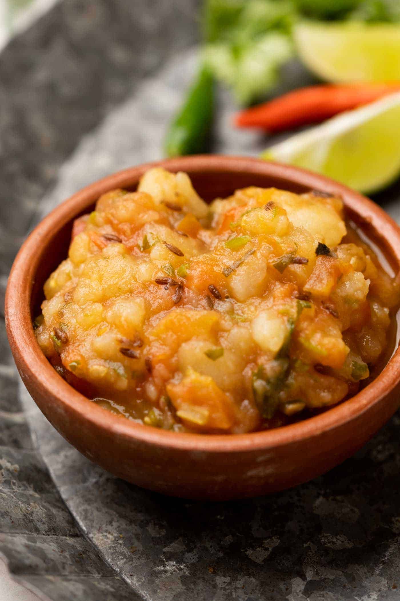 Picture of potato curry served in a brown terracotta bowl