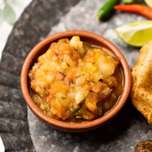 Picture of potato curry served in a brown terracotta bowl with puri on the side