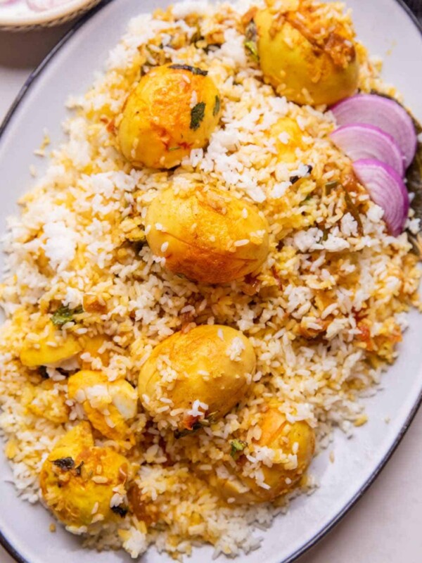 Egg Biryani served on a white platter with onion raita on the side