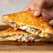 A hand picking up a slice of hung curd sandwich
