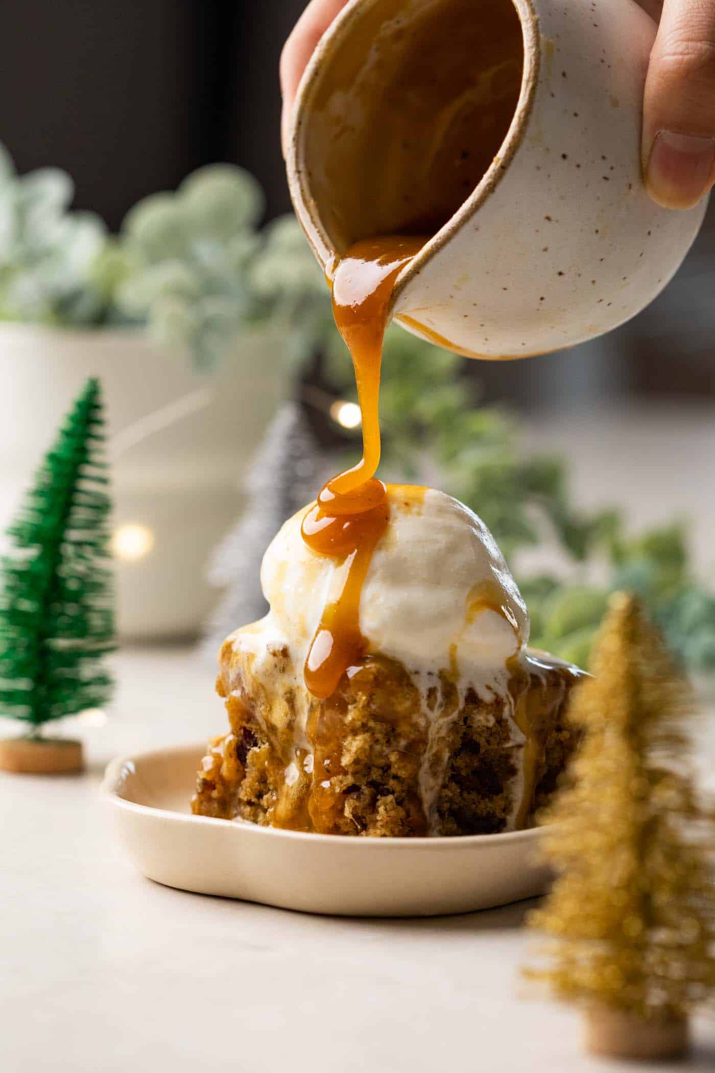 Toffee sauce being poured on sticky toffee pudding