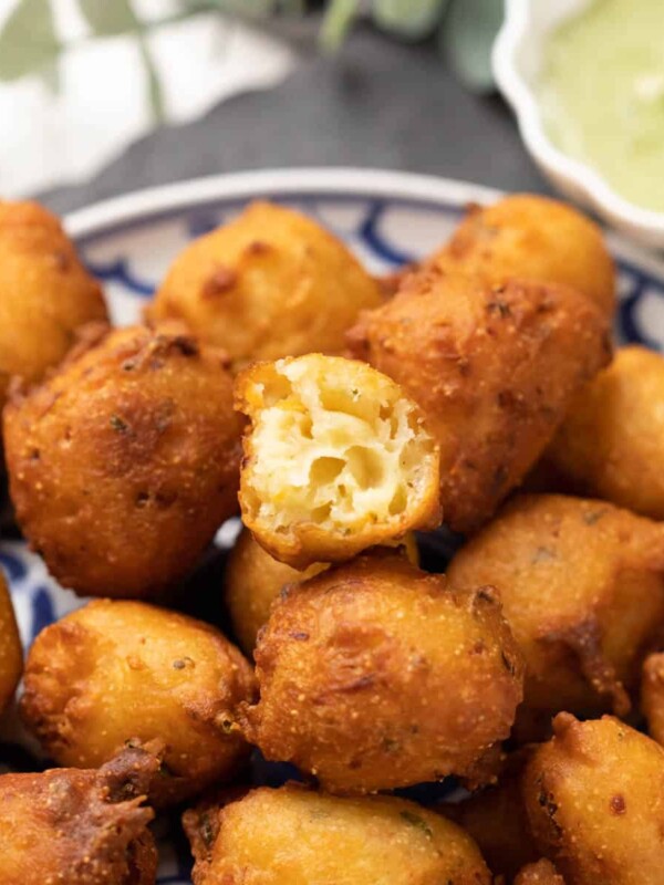 mysore curd bonda served on a white and blue plate with one bonda cut open