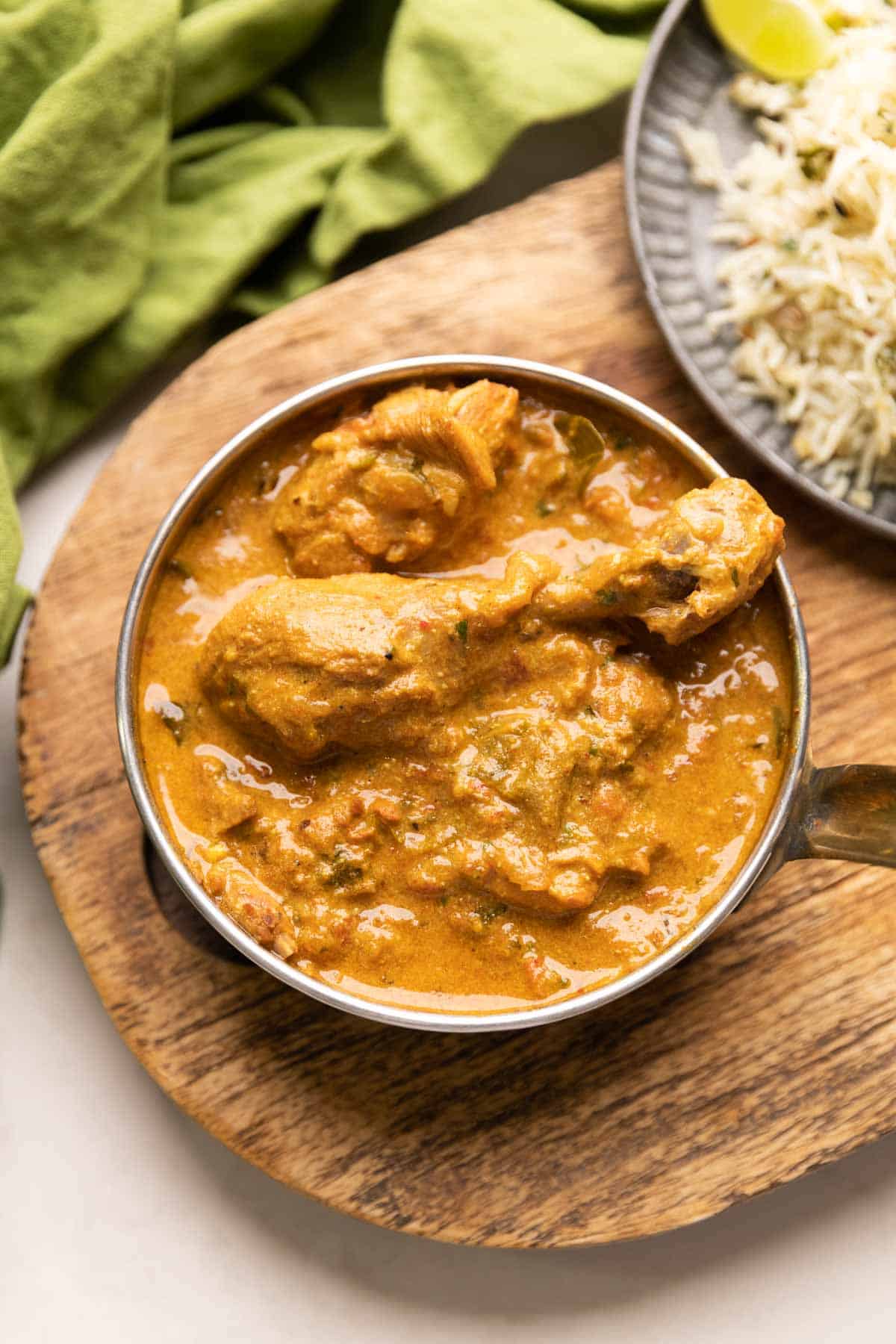 a bowl of coconut chicken curry with a side of jeera rice