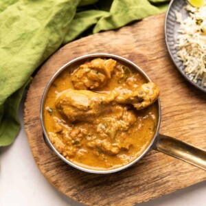 a bowl of coconut chicken curry with a side of jeera rice