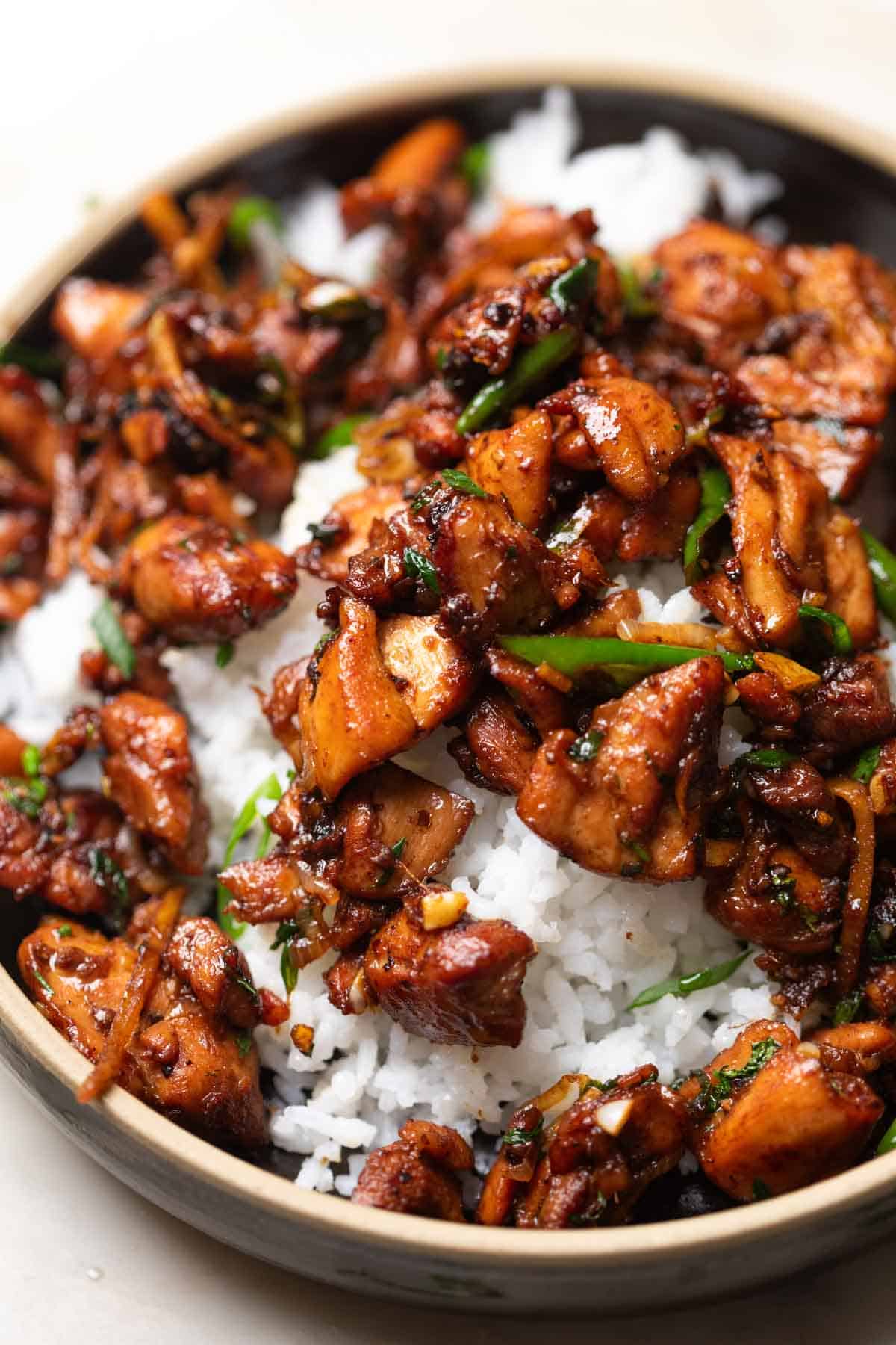 a close up of ginger chicken stir fry served over some white rice in a bowl