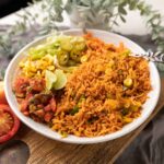 Instant Pot mexican rice served in a bowl with letttuce, corn, salsa, jalapenos and lime wedges on the side.