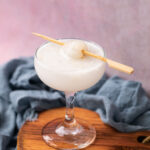 lychee soda served in a glass topped with a lychee on a toothpick