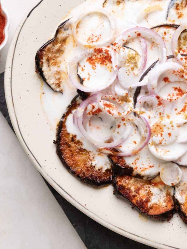 platter with fried eggplant slices and sliced onion topped with a curd mix