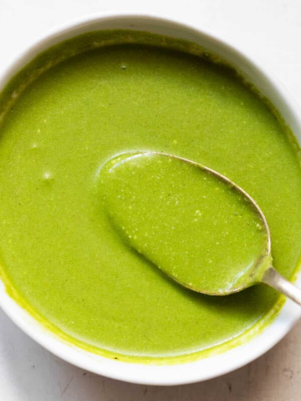 mint chutney served in a white bowl with a spoonful of chutney being taken out