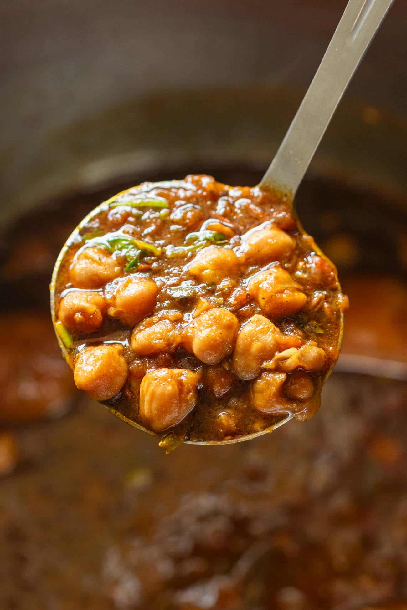 Love Indian food? Chana Masala or chhole masala is an easy and incredibly tasty chickpeas and potato curry. Its got a punch of flavour from the spices, and this recipe has instructions for instant pot, traditional pressure cooker and stovetop. The best part is that apart from being healthy, its vegan and gluten free. image of a ladle full of chana masala