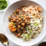Pressure cooker chana masala served in a bowl with rice and onions on the side